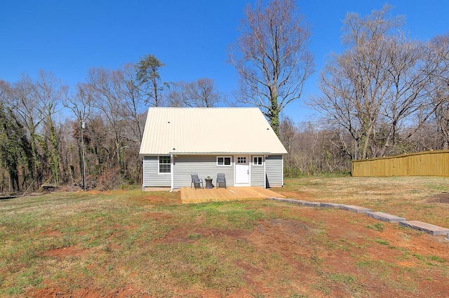 rear view of house featuring metal roof, a lawn, a deck, and fence