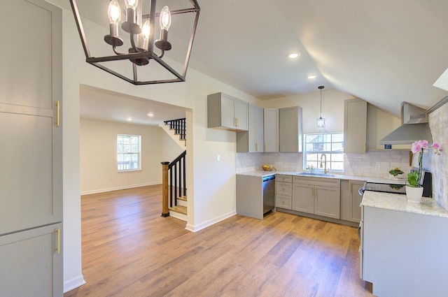 kitchen with tasteful backsplash, gray cabinetry, wall chimney range hood, a wealth of natural light, and a sink