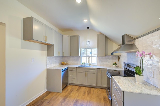 kitchen featuring a sink, wall chimney range hood, gray cabinetry, and stainless steel appliances