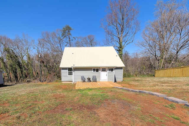 back of property featuring a wooden deck, a yard, fence, and metal roof