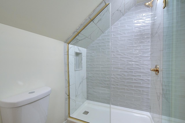 bathroom with a tile shower and toilet