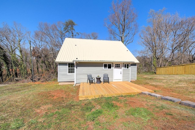 rear view of property with metal roof, a lawn, fence, and a wooden deck