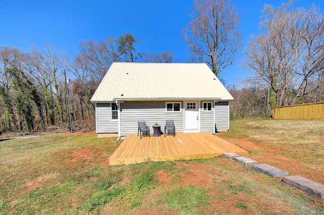 rear view of house featuring metal roof, a lawn, fence, and a wooden deck