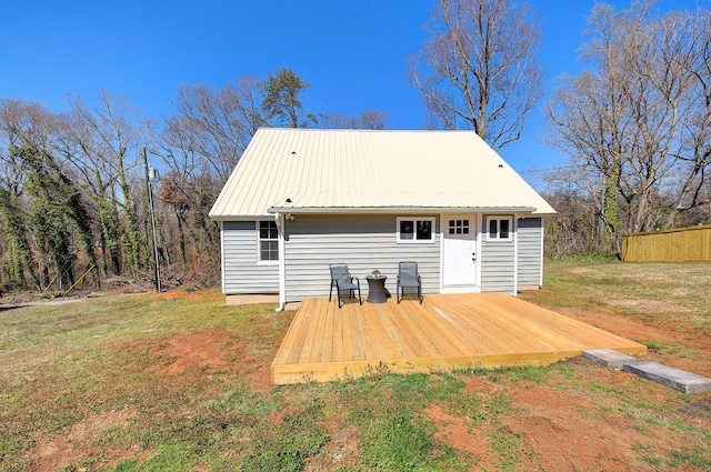 rear view of property with a lawn, a wooden deck, and metal roof