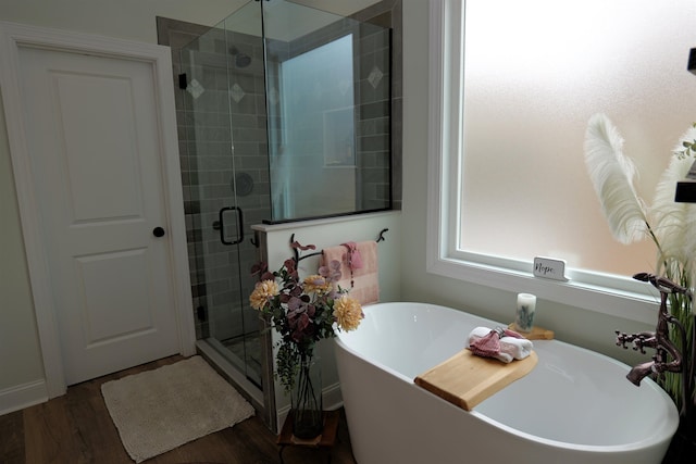 bathroom with a stall shower, a freestanding bath, and wood finished floors