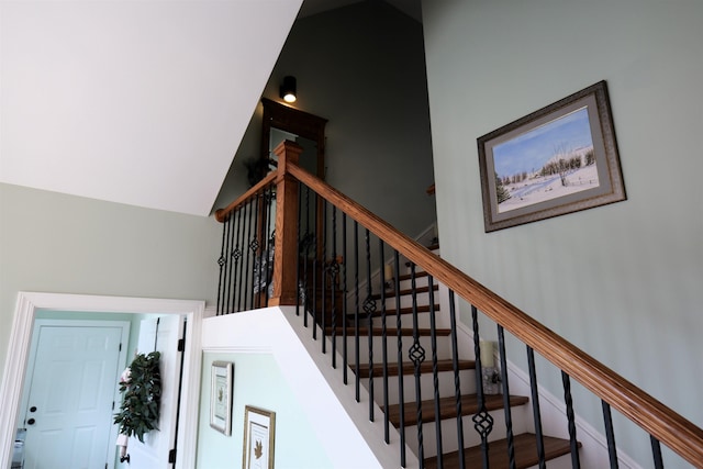 stairway with baseboards and a high ceiling