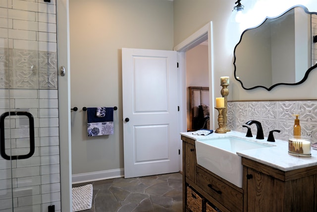 bathroom with stone finish flooring, baseboards, a stall shower, and vanity