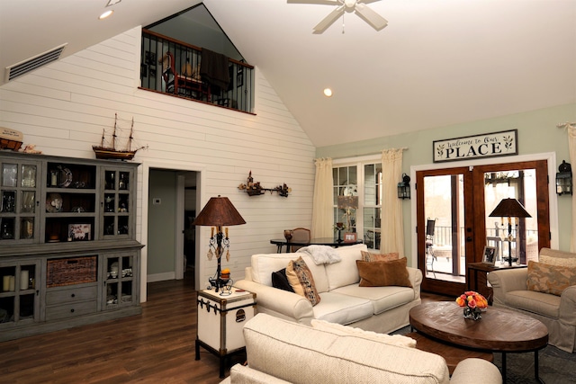 living area featuring visible vents, high vaulted ceiling, dark wood-style floors, wood walls, and ceiling fan