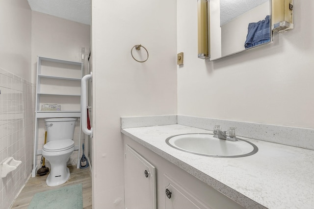 bathroom featuring tile walls, toilet, a textured ceiling, and vanity