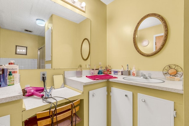 bathroom with vanity, visible vents, and a textured ceiling