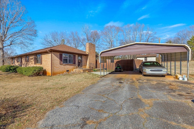 view of front facade featuring a detached carport, fence, a chimney, aphalt driveway, and brick siding