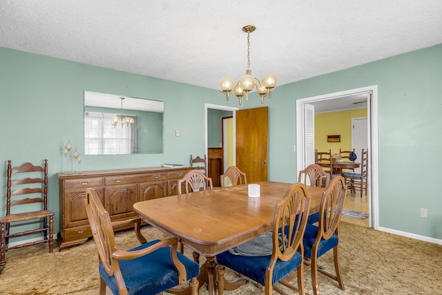 dining space featuring a notable chandelier, light colored carpet, a textured ceiling, and baseboards