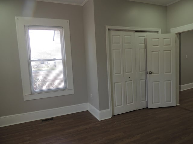 unfurnished bedroom with visible vents, multiple windows, and dark wood-style floors