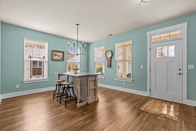 foyer with dark wood-style floors, visible vents, an inviting chandelier, and baseboards