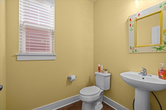 bathroom featuring wood finished floors, toilet, baseboards, and a sink