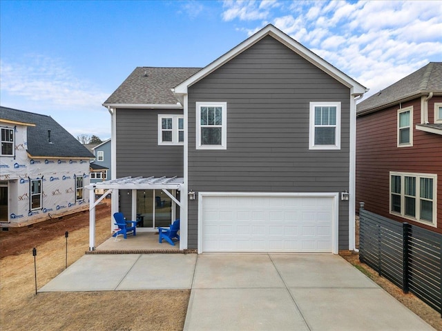 back of property featuring an attached garage, driveway, a patio, and fence