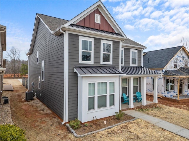 view of front facade featuring board and batten siding, a shingled roof, metal roof, a patio area, and a standing seam roof