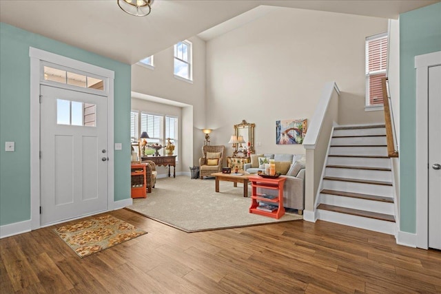 foyer entrance featuring stairs, a high ceiling, wood finished floors, and baseboards