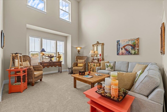 living room featuring baseboards, light carpet, plenty of natural light, and a high ceiling