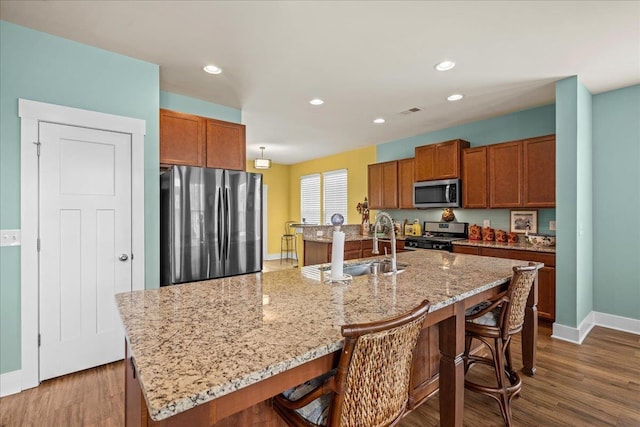 kitchen with stainless steel appliances, a breakfast bar, dark wood-style floors, and visible vents