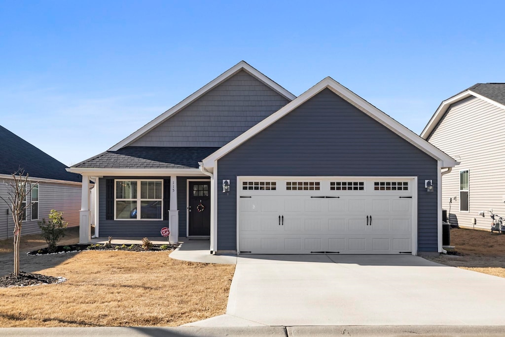 view of front of house with an attached garage, concrete driveway, and a shingled roof