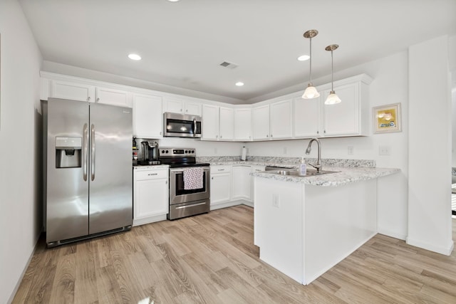 kitchen with light wood finished floors, appliances with stainless steel finishes, a peninsula, white cabinetry, and a sink