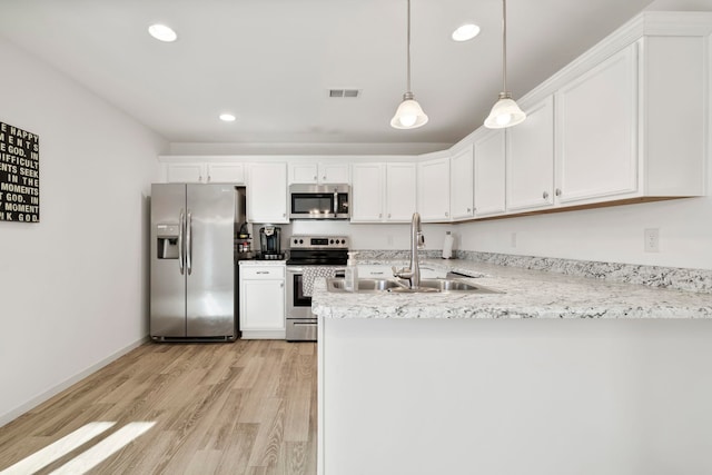 kitchen featuring visible vents, light wood-type flooring, a sink, appliances with stainless steel finishes, and a peninsula