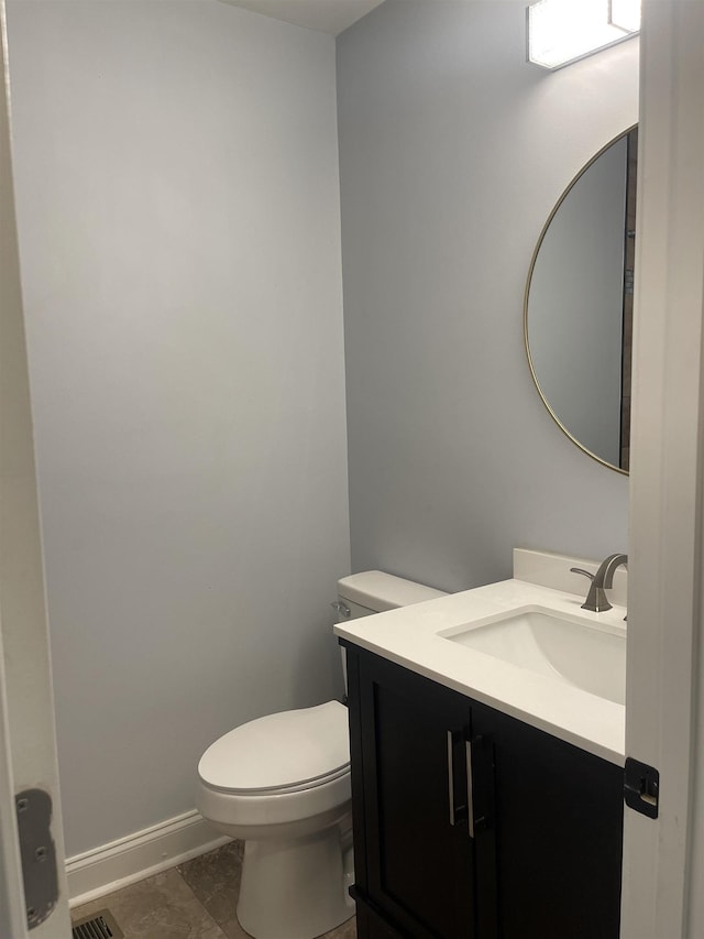 bathroom featuring toilet, vanity, and baseboards