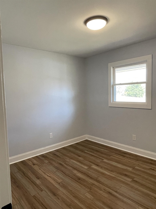 unfurnished room with dark wood-type flooring and baseboards