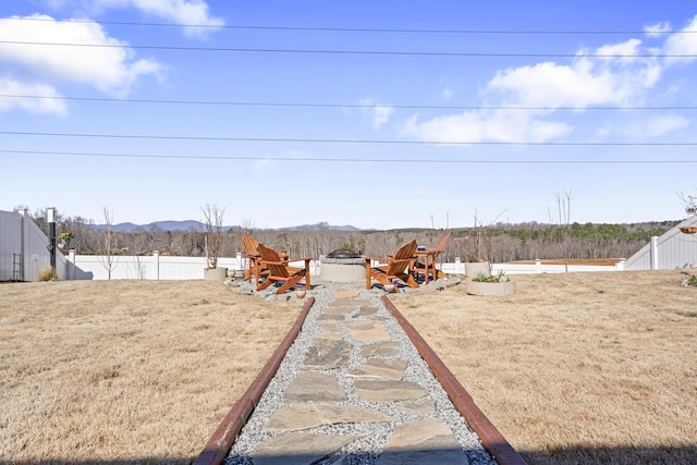 view of yard featuring a mountain view, an outdoor fire pit, and fence