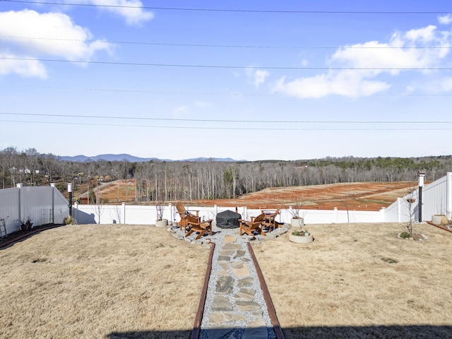 view of yard with a mountain view, a fire pit, and a fenced backyard