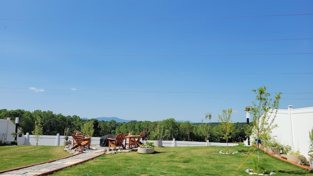 view of yard featuring a wooded view and a fenced backyard