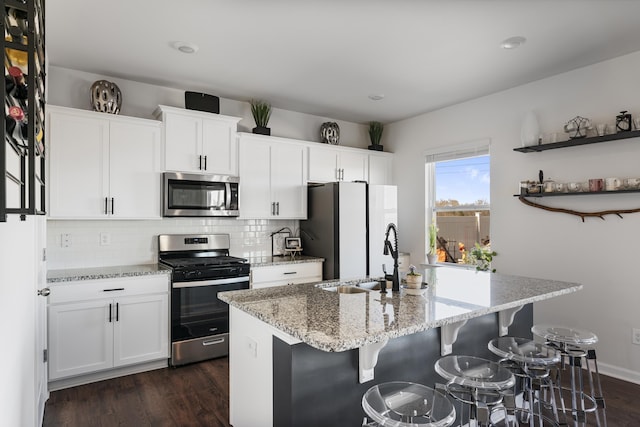 kitchen featuring dark wood finished floors, decorative backsplash, stainless steel appliances, and a sink