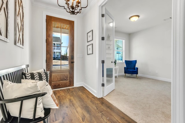 foyer entrance featuring dark wood-style floors, baseboards, a notable chandelier, and ornamental molding