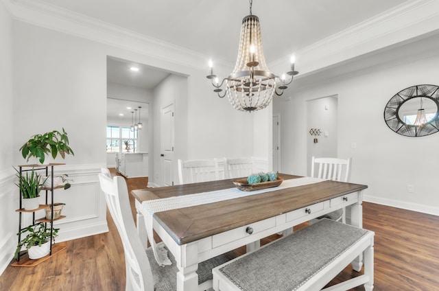 dining room featuring ornamental molding, wood finished floors, a wainscoted wall, and a chandelier