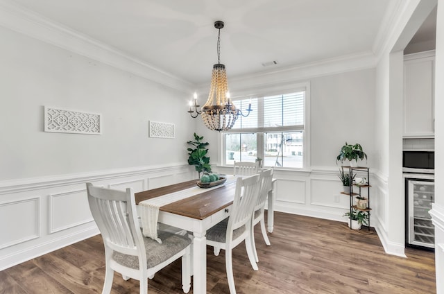 dining area with an inviting chandelier, crown molding, wood finished floors, and beverage cooler