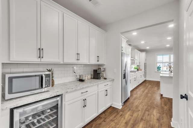 kitchen featuring visible vents, beverage cooler, decorative backsplash, appliances with stainless steel finishes, and white cabinetry