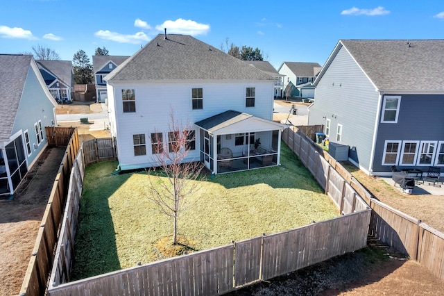 back of house with a residential view, a fenced backyard, a lawn, and a sunroom