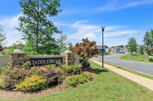 community sign featuring a yard and a residential view