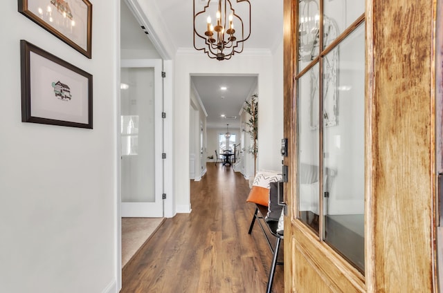 foyer entrance with dark wood-type flooring, baseboards, crown molding, and an inviting chandelier