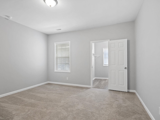 carpeted spare room featuring a healthy amount of sunlight and baseboards