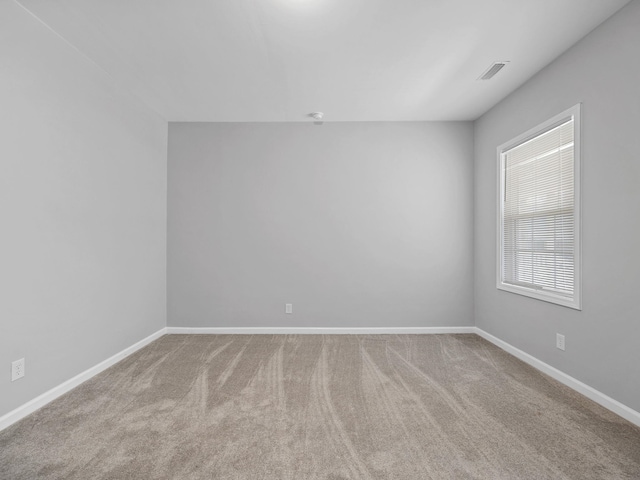 empty room featuring visible vents, baseboards, and carpet