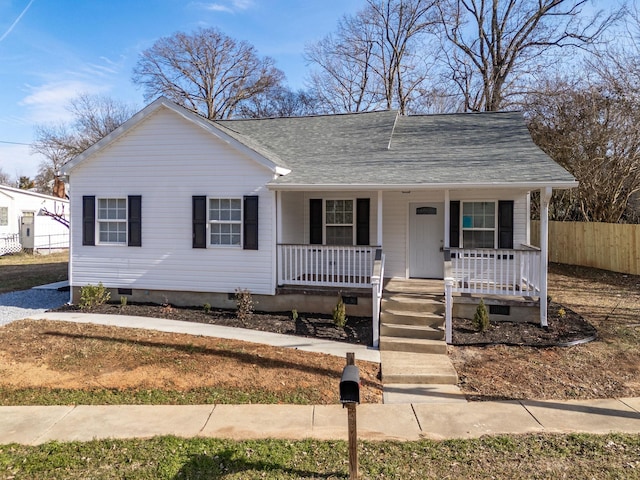 view of front facade featuring crawl space, a porch, a shingled roof, and fence