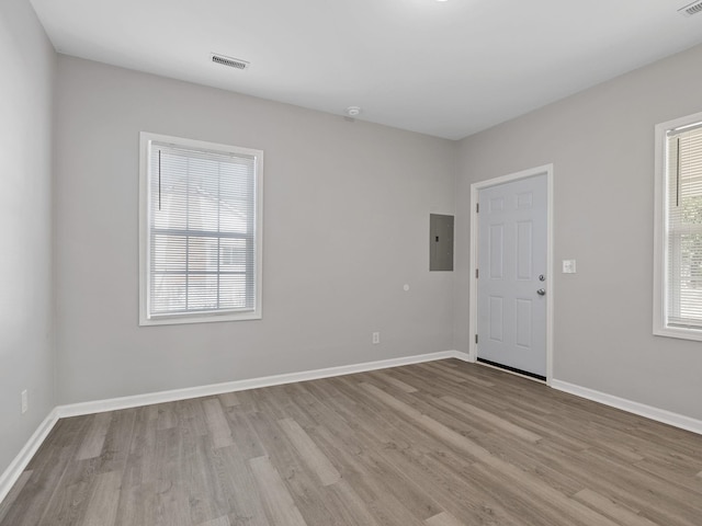 unfurnished room with electric panel, visible vents, baseboards, and wood finished floors