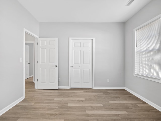 unfurnished bedroom with visible vents, baseboards, a closet, and light wood-style flooring