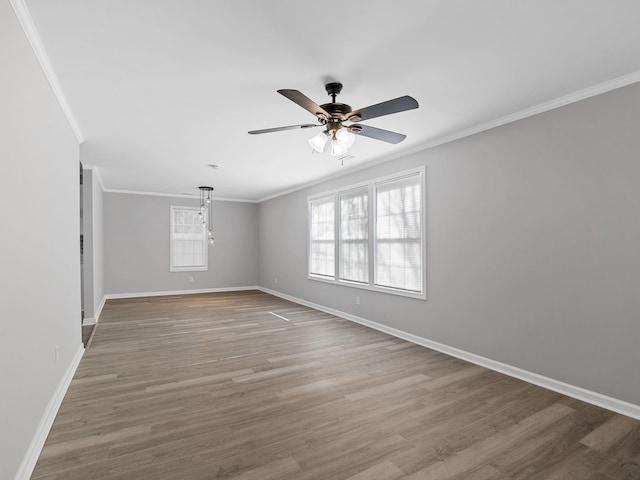 empty room featuring wood finished floors, crown molding, a ceiling fan, and baseboards