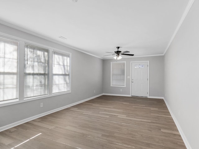 spare room with baseboards, wood finished floors, ceiling fan, and ornamental molding