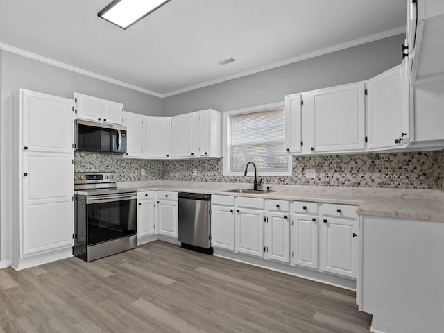 kitchen featuring white cabinetry, light wood-type flooring, appliances with stainless steel finishes, and a sink