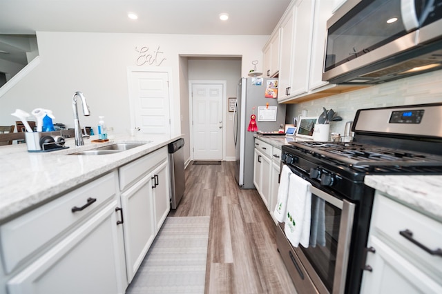 kitchen featuring a sink, tasteful backsplash, white cabinetry, and stainless steel appliances