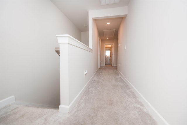 corridor with attic access, carpet, and baseboards